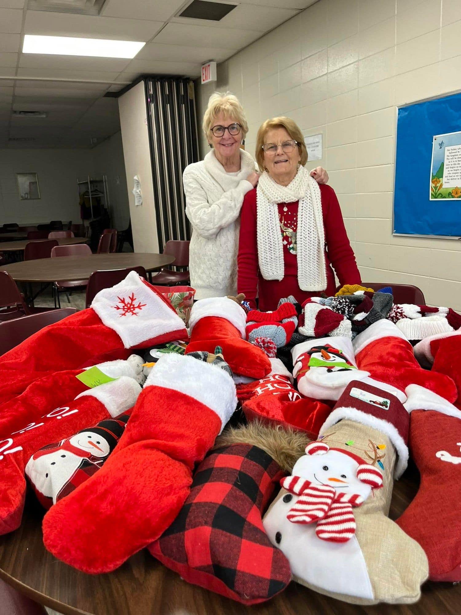 Stockings of Love volunteers standing behind a table of finished stockings