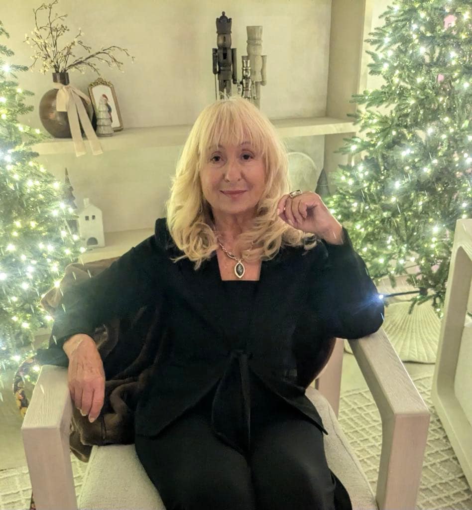 Janice Ford-Spencer seated beside a lit Christmas tree