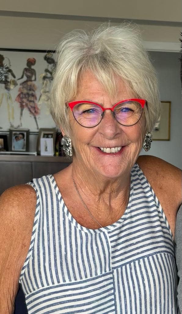 Patricia Tudor smiling in red glasses